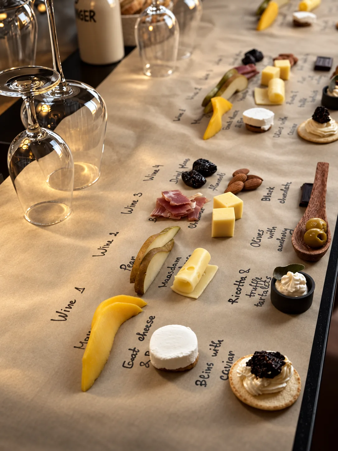 A tasting table laid with cheese, fruit and small bites beside upturned wine glasses